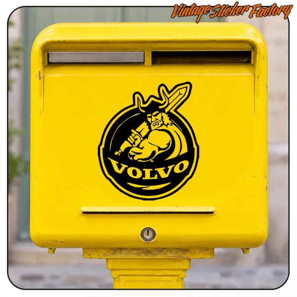 Adhesivo con figura vikinga y texto VOLVO aplicado en un buzón amarillo