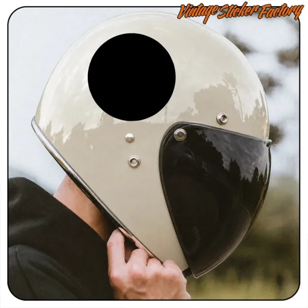 Adhesivo circular negro sobre un casco blanco con visera oscura