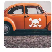 Weißer Schädel mit gekreuzten Knochen an der Tür eines klassischen orangefarbenen Autos