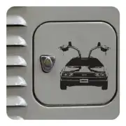 Pegatina del DeLorean colocada junto a un emblema sobre una superficie gris
