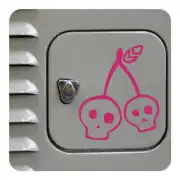 Autocollant Cherry Skull avec deux têtes de mort et des cerises posé sur une surface grise