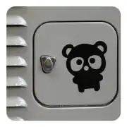 Ourson noir collé sur une surface carrée à côté d’une commande métallique
