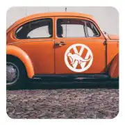 Pegatina circular con dinosaurio aplicada en la puerta de un Volkswagen Escarabajo naranja