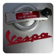Rotes Vespa-Logo auf einer Metallfläche neben einem Verschluss