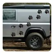 Varias pegatinas de huellas de perro negras aplicadas en el lateral de un vehículo