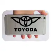 Pegatina negra con emblema alado y texto TOYODA aplicada en un teléfono móvil.