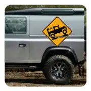 Aufkleber mit Geländewagen auf gelbem Schild an der Seite eines grauen Fahrzeugs