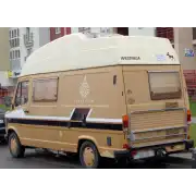 Parte trasera de una camper beige con emblema lateral y gráficos decorativos