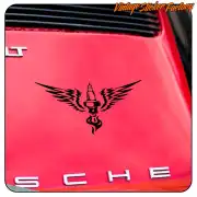 Winged spark plug in black adhesive applied to the red bonnet of a car