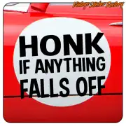Schwarzer Text „HONK IF ANYTHING FALLS OFF“ auf der roten Karosserie eines Fahrzeugs