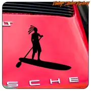 Silhouette einer Person mit Dreadlocks auf einem SUP-Board, auf der roten Karosserie eines Fahrzeugs angebracht